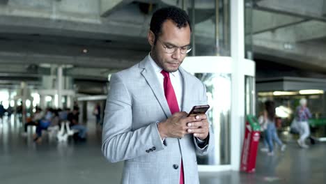 Businessman-using-smartphone-at-railway-station